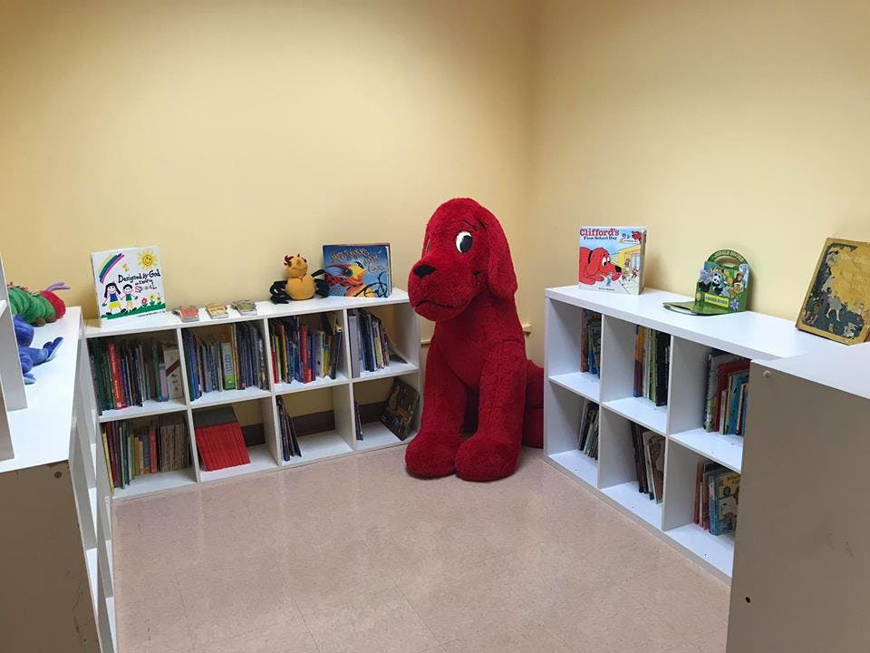 Large red dog plush toy in a room with bookshelves
