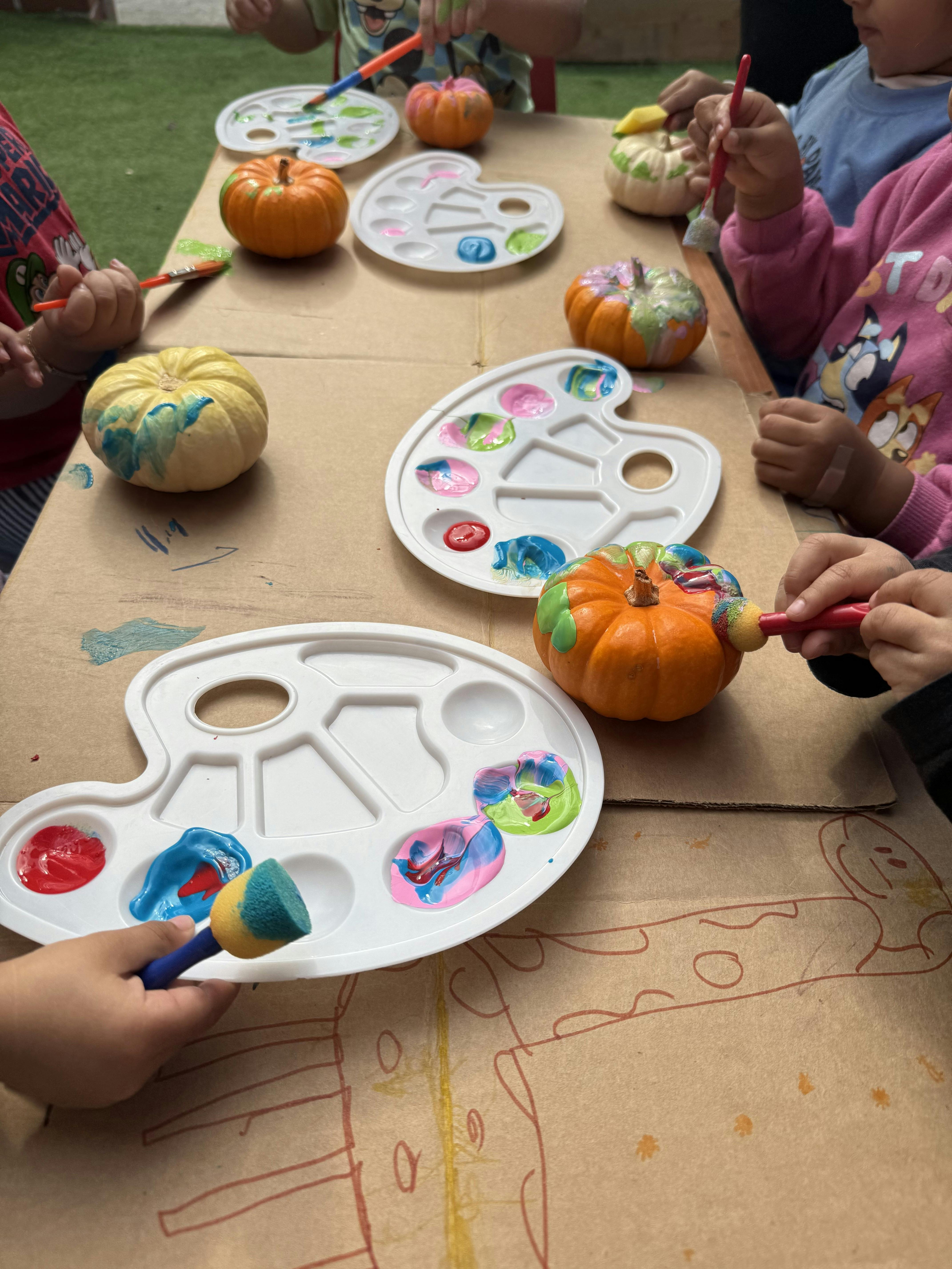 Children painting pumpkins at a table