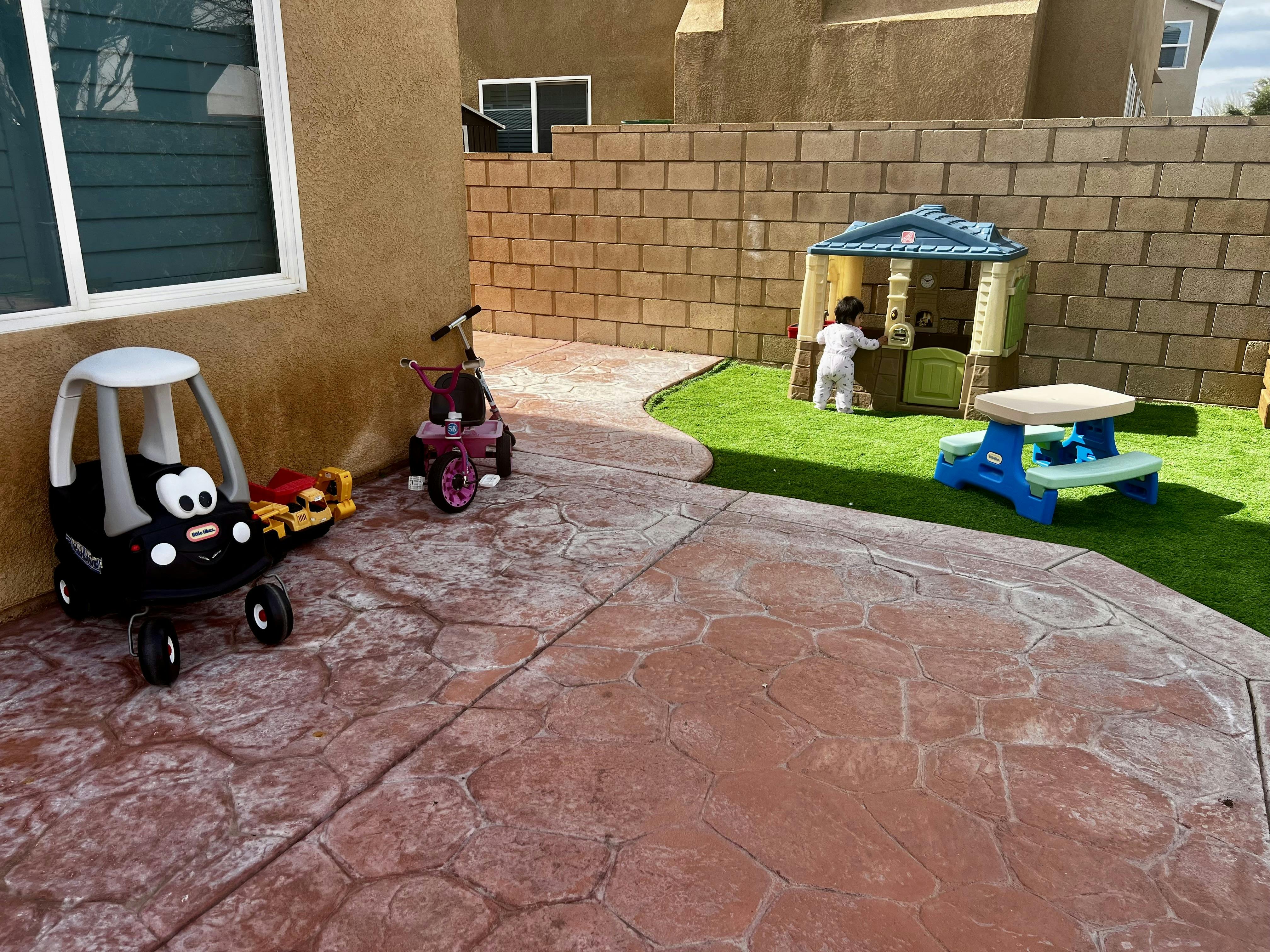 Child in pajamas playing in a toy house on artificial grass