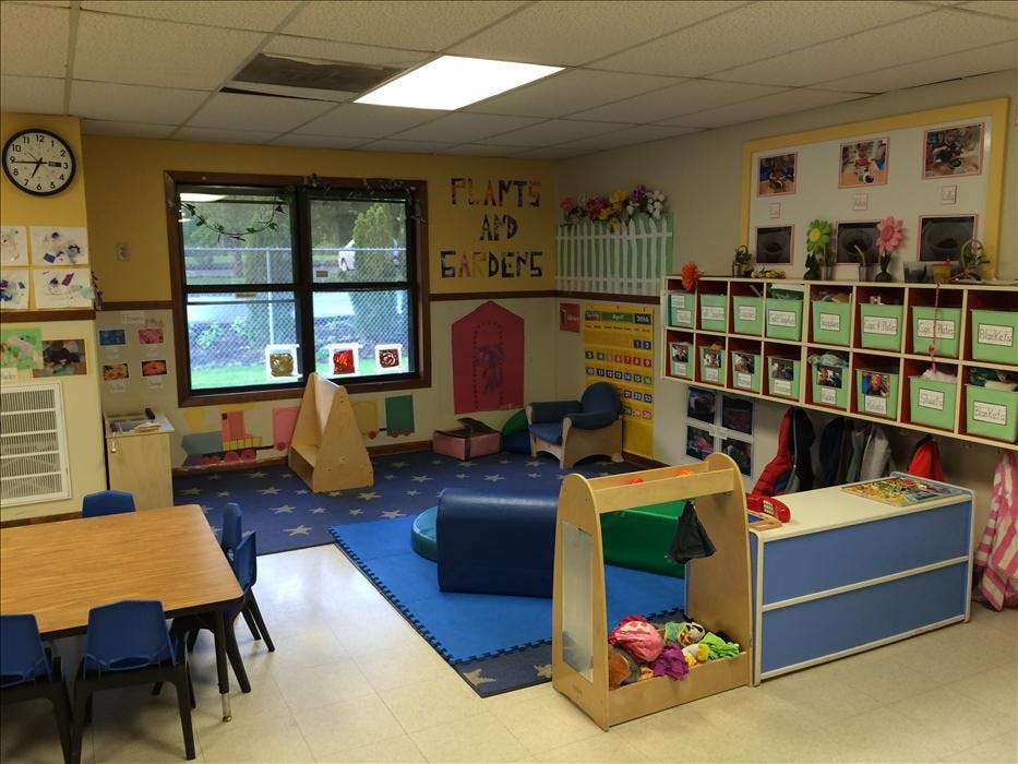 Classroom with child-sized furniture, a play area, and activity supplies