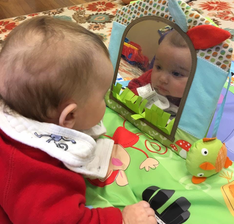 Child looking at reflection in a mirror on a playmat