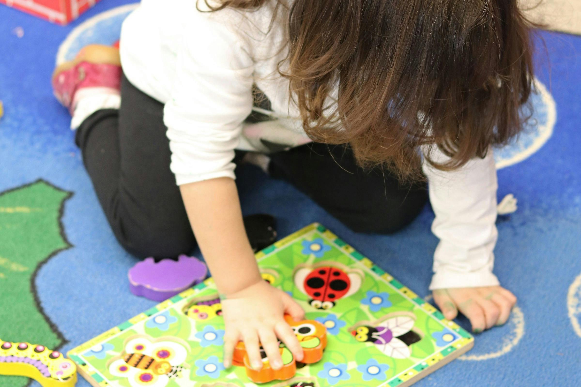 Child playing with a puzzle on the floor