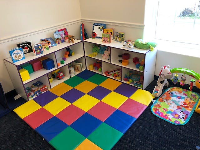 Playroom with colorful floor mats and shelves filled with toys