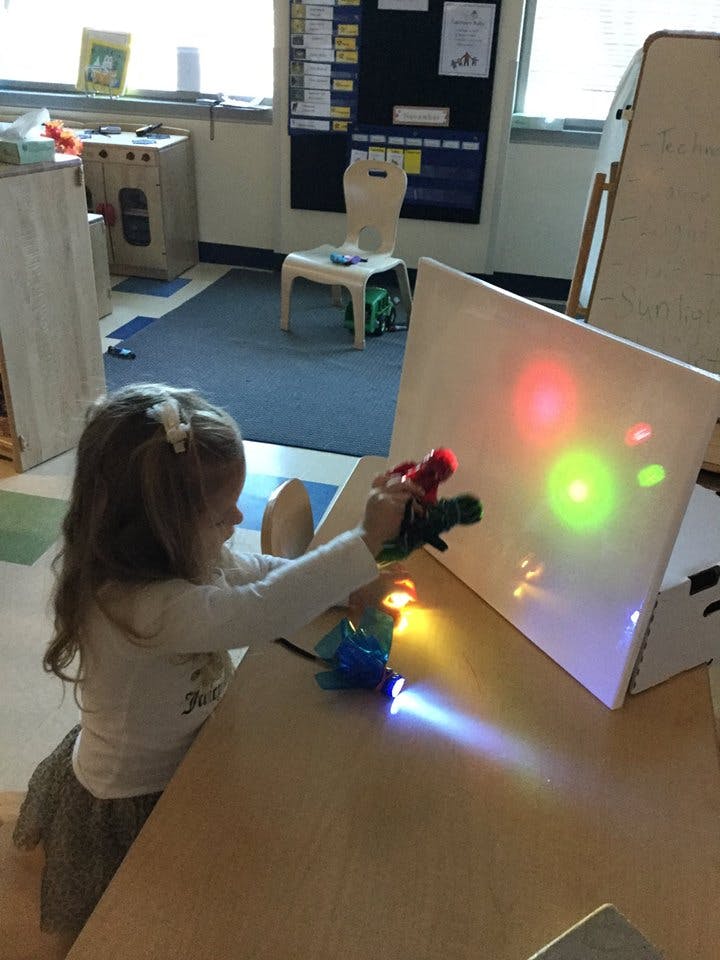 Child playing with light toys on a table in a classroom