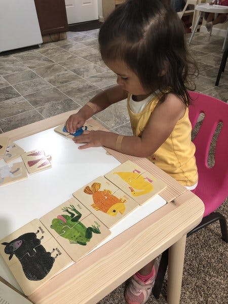 Child playing with wooden animal puzzles at a small table