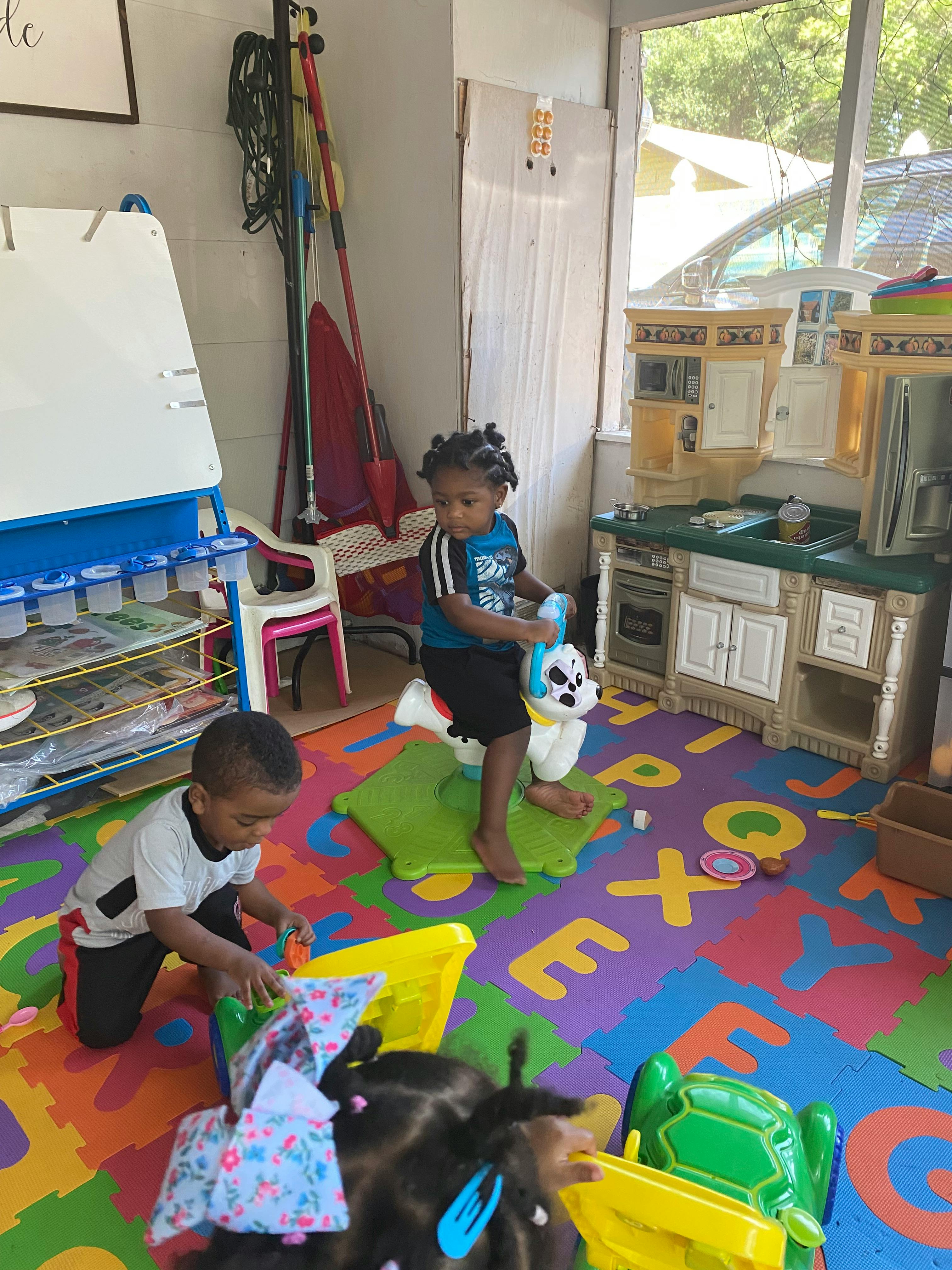 Children playing on a colorful alphabet mat in a room