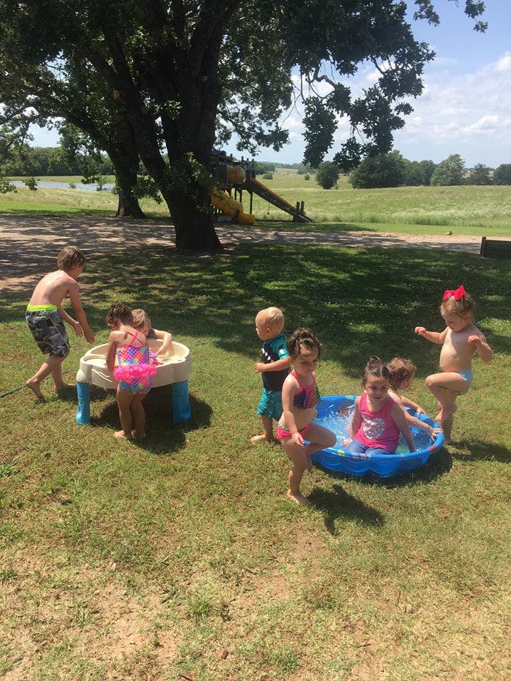 Children playing in small pools and a water table outdoors