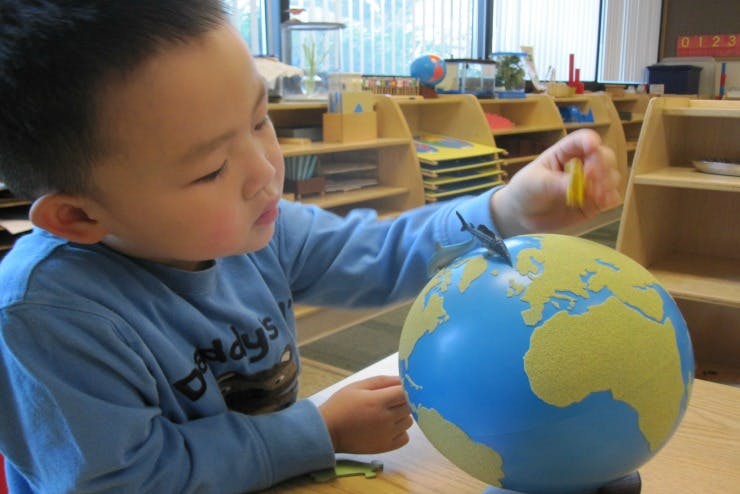 Child interacting with a globe in a classroom