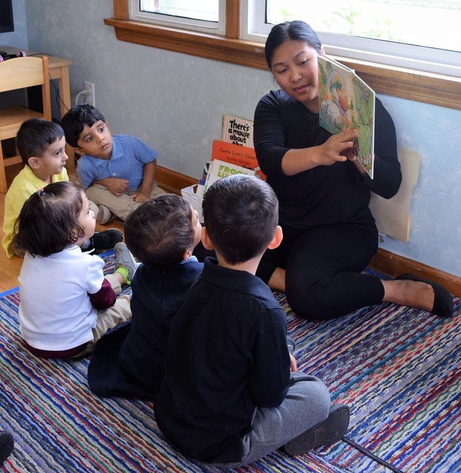 Person reading a book to children in a classroom