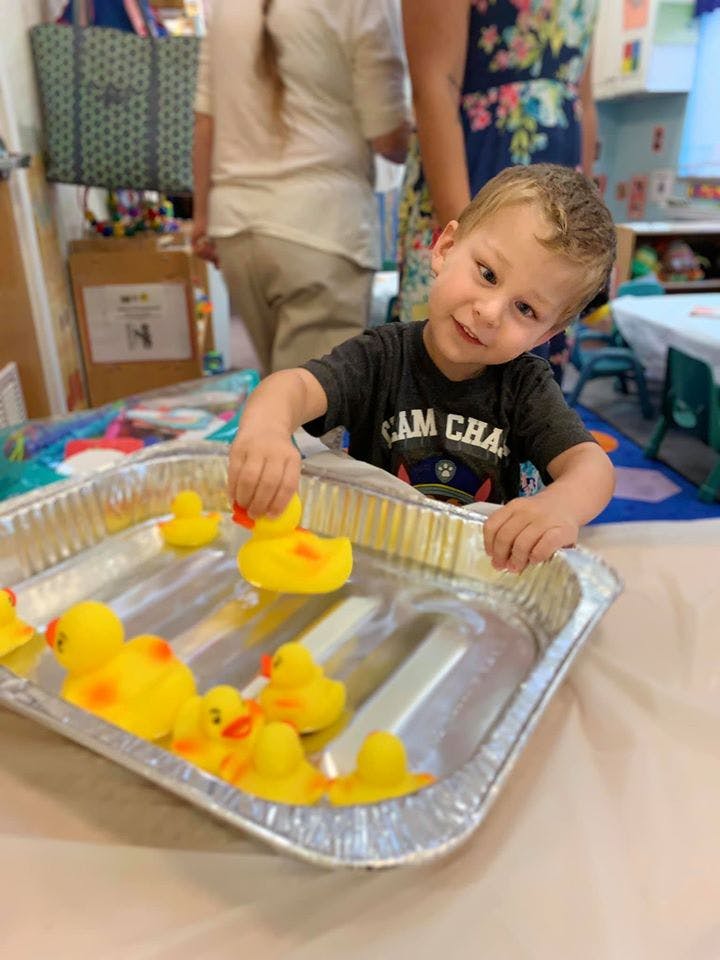 Child playing with rubber ducks in a foil pan