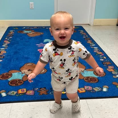 Child standing on a blue rug with teddy bears