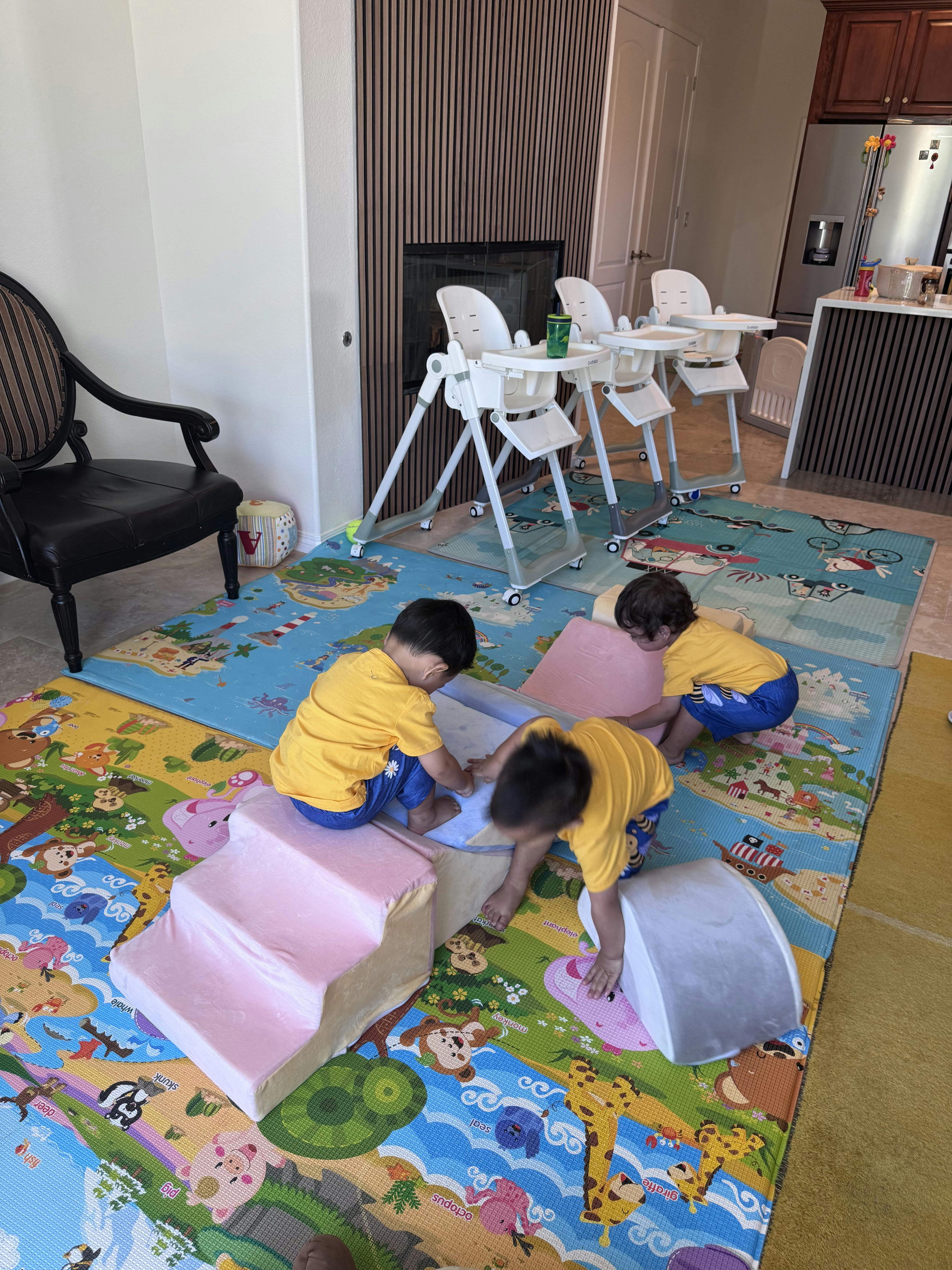 Three children playing on foam climbing blocks on a patterned floor mat