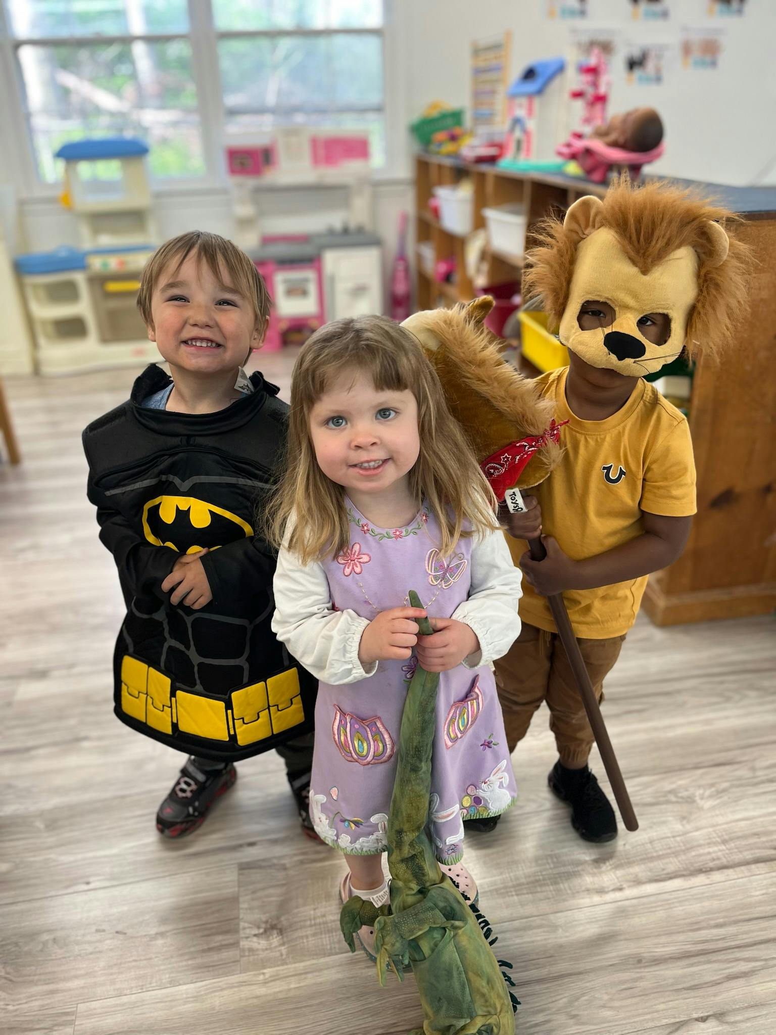 Three children in costumes, one dressed as Batman, one in a lion costume