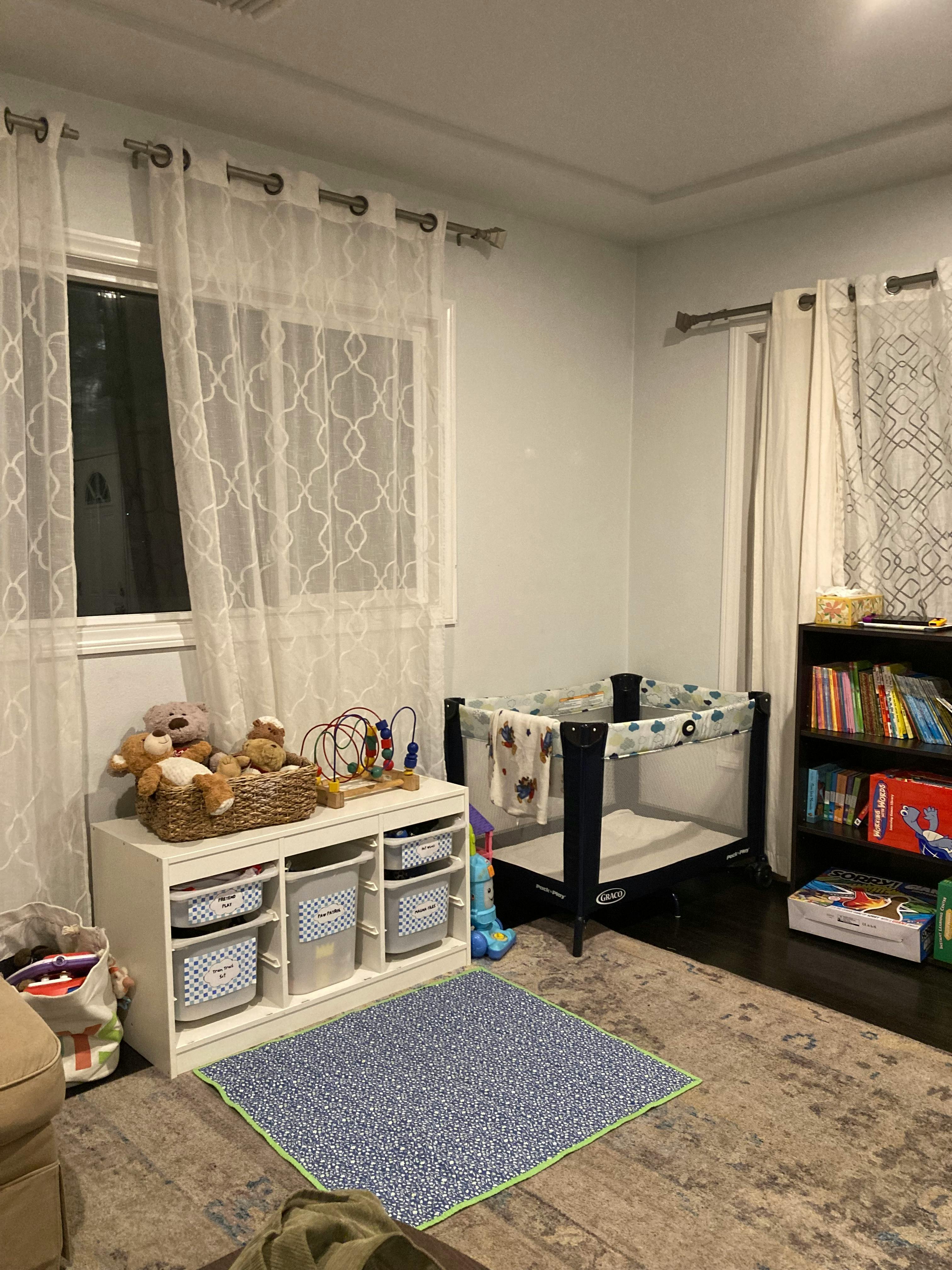 Nursery room with a crib, toy storage, and bookshelf