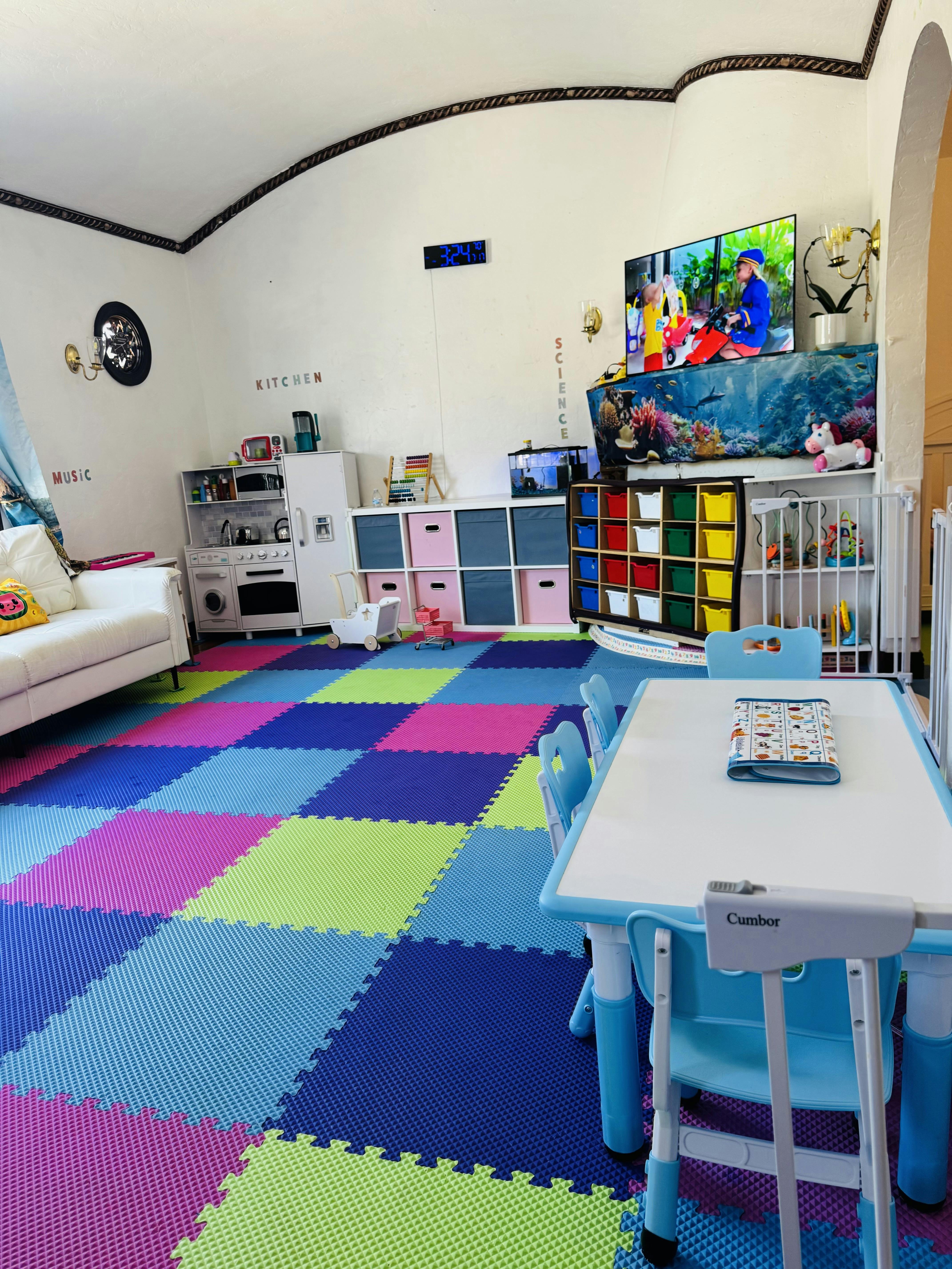 Playroom with colorful foam floor tiles, small table and chairs, and storage units