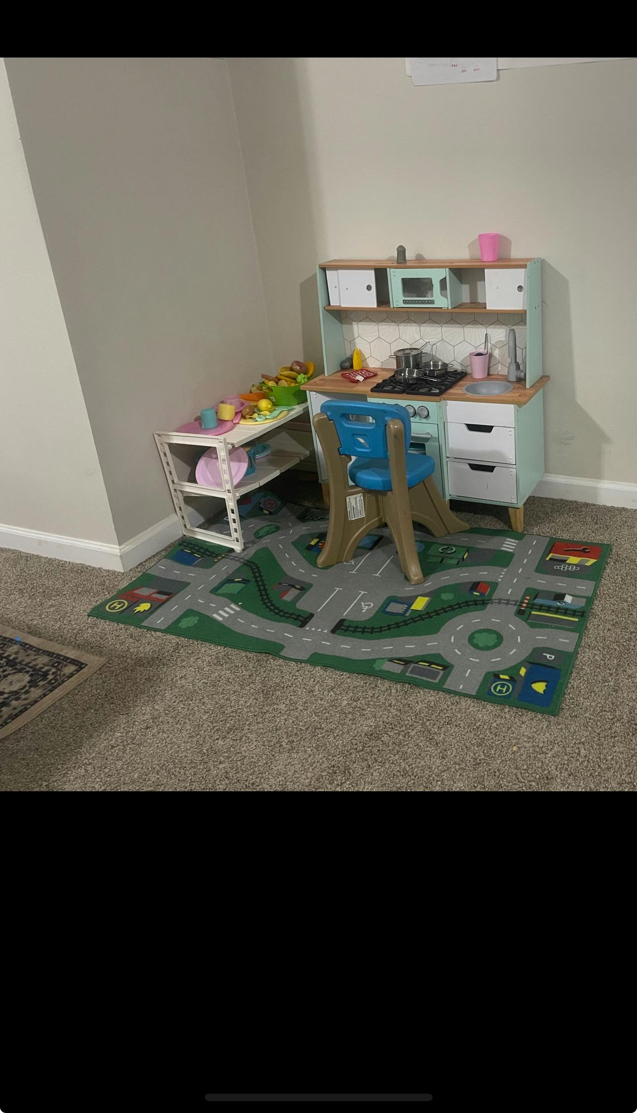 Child's play kitchen set with a blue chair on a road map rug