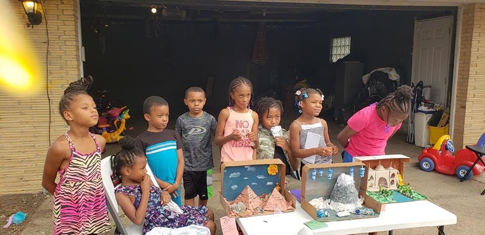 Group of children standing around a table with science projects