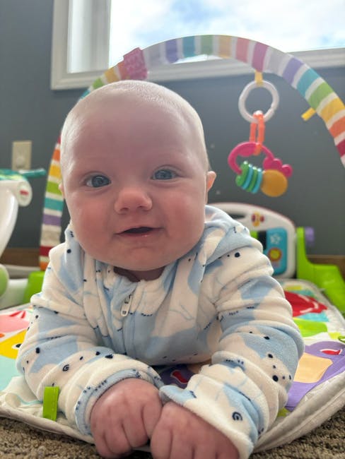 Child on a playmat looking up at the camera