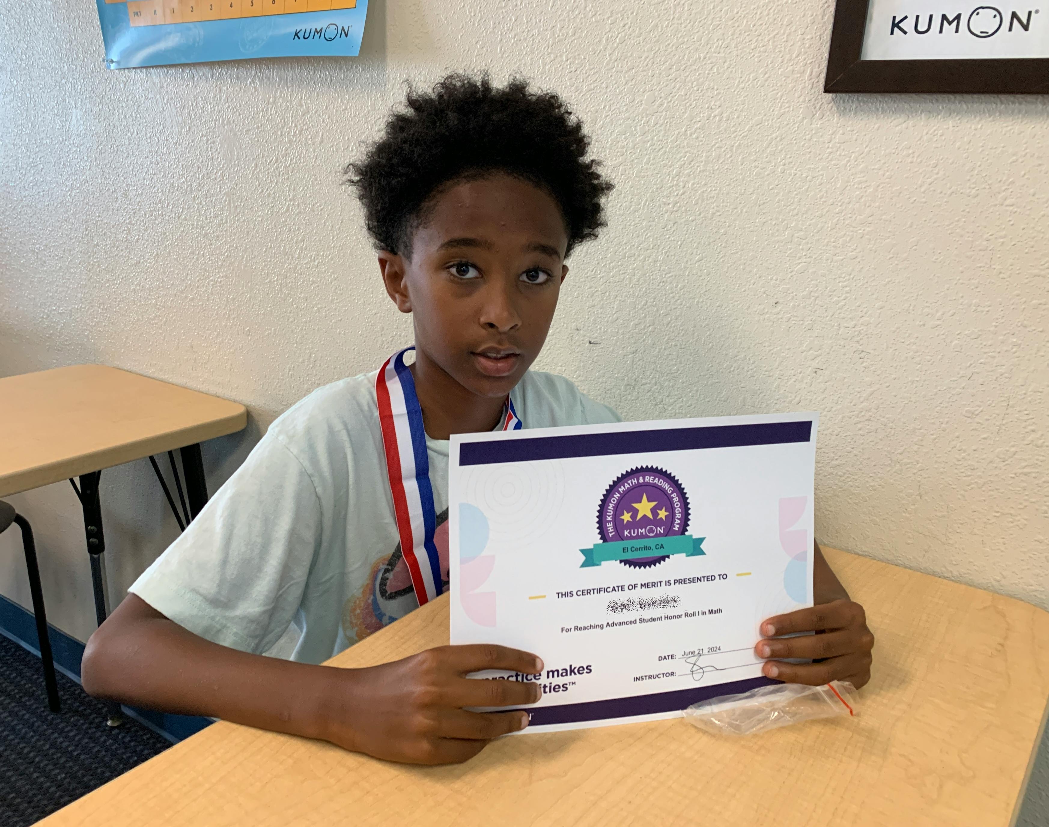 Child with a medal around their neck, holding a Kumon certificate