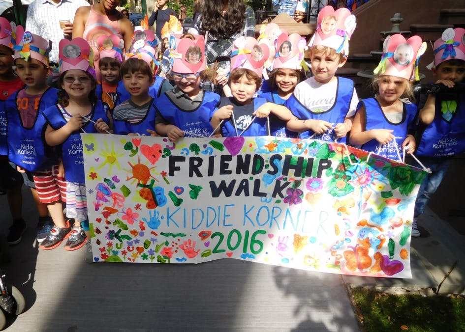 Children holding a banner that reads "Friendship Walk Kiddie Korner 2016"