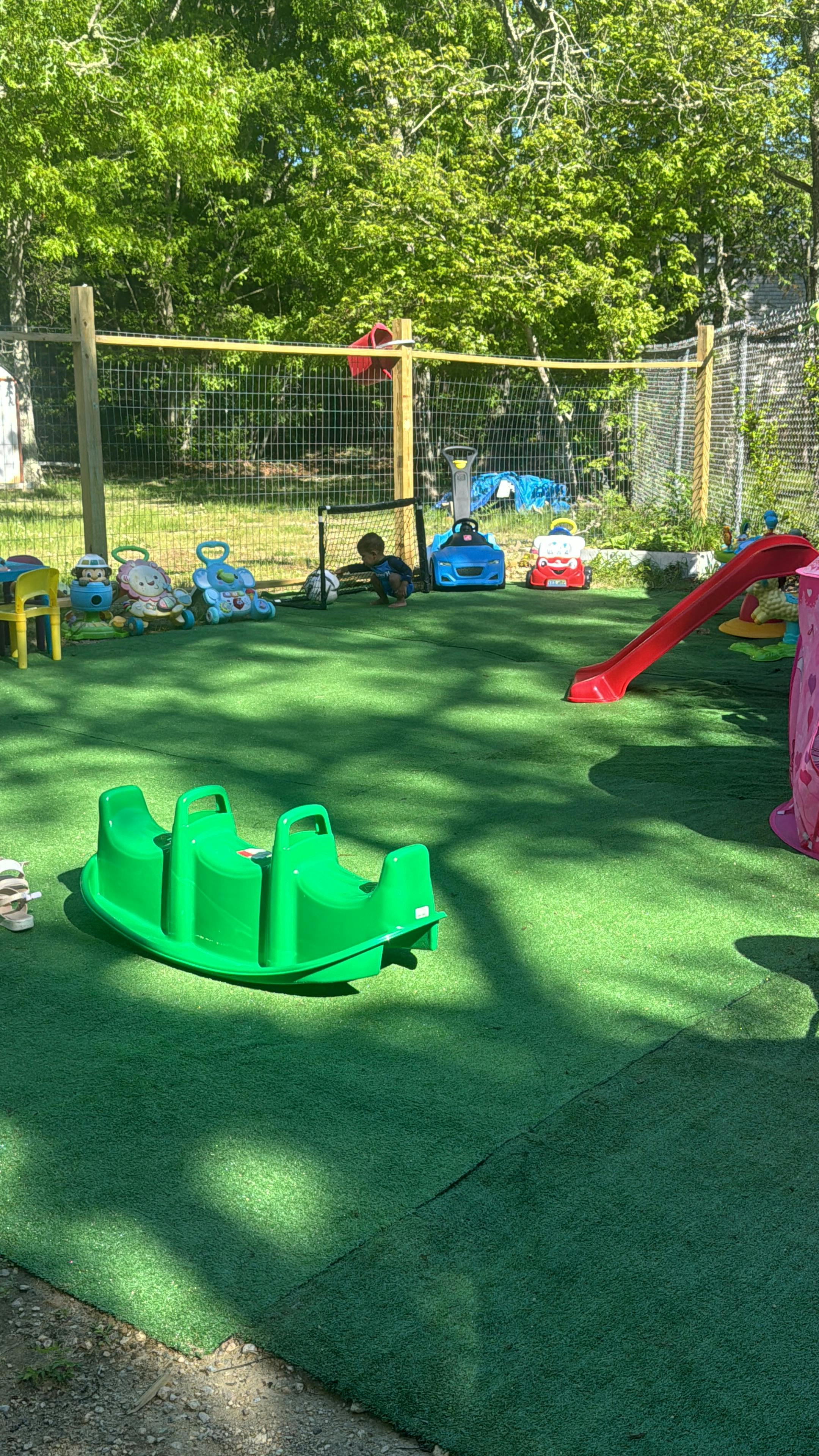 Child playing with a soccer ball on a playground with toys and a slide