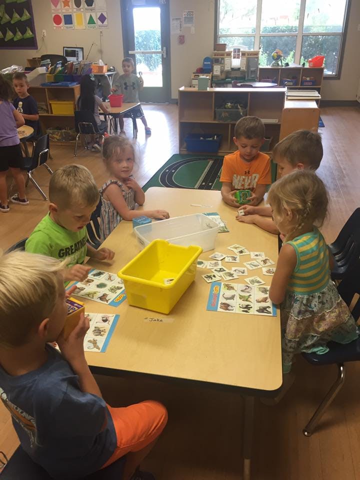 Children sitting at a table with cards and containers