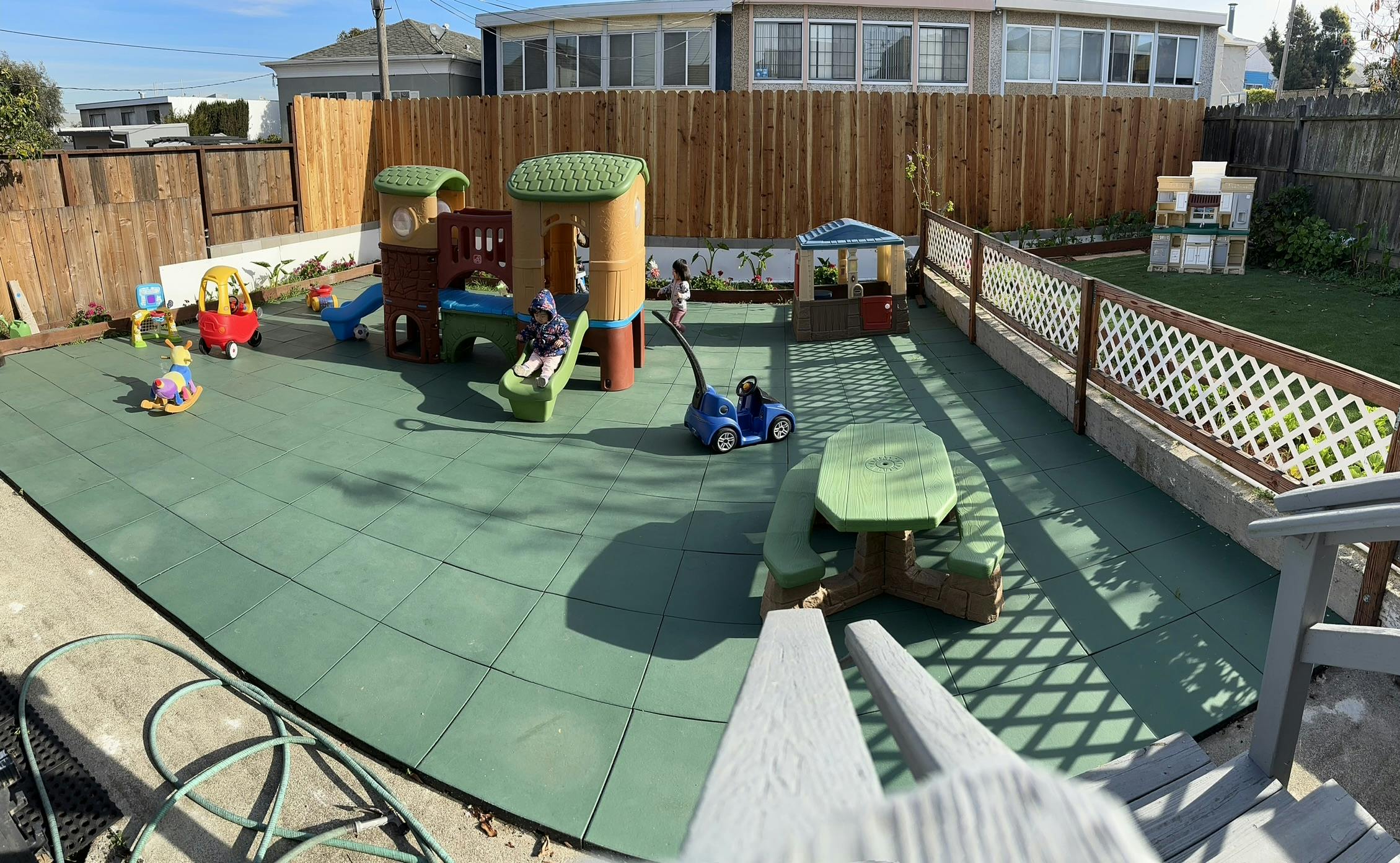 Outdoor playground with play structures and green safety matting