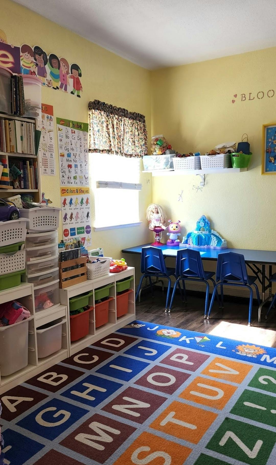Classroom with an alphabet rug, storage shelves, and a table with chairs