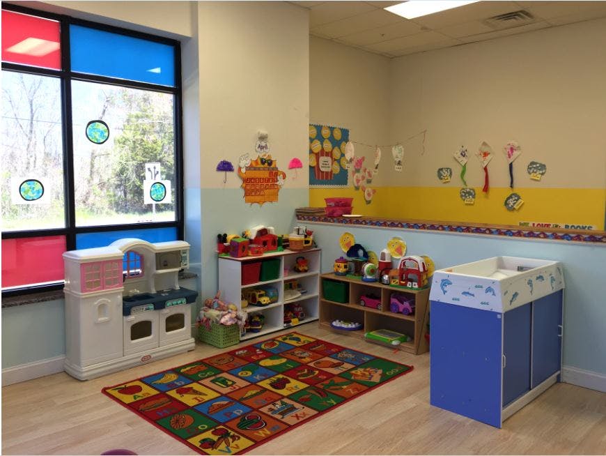 Playroom with colorful rug, shelves of toys, and a changing table