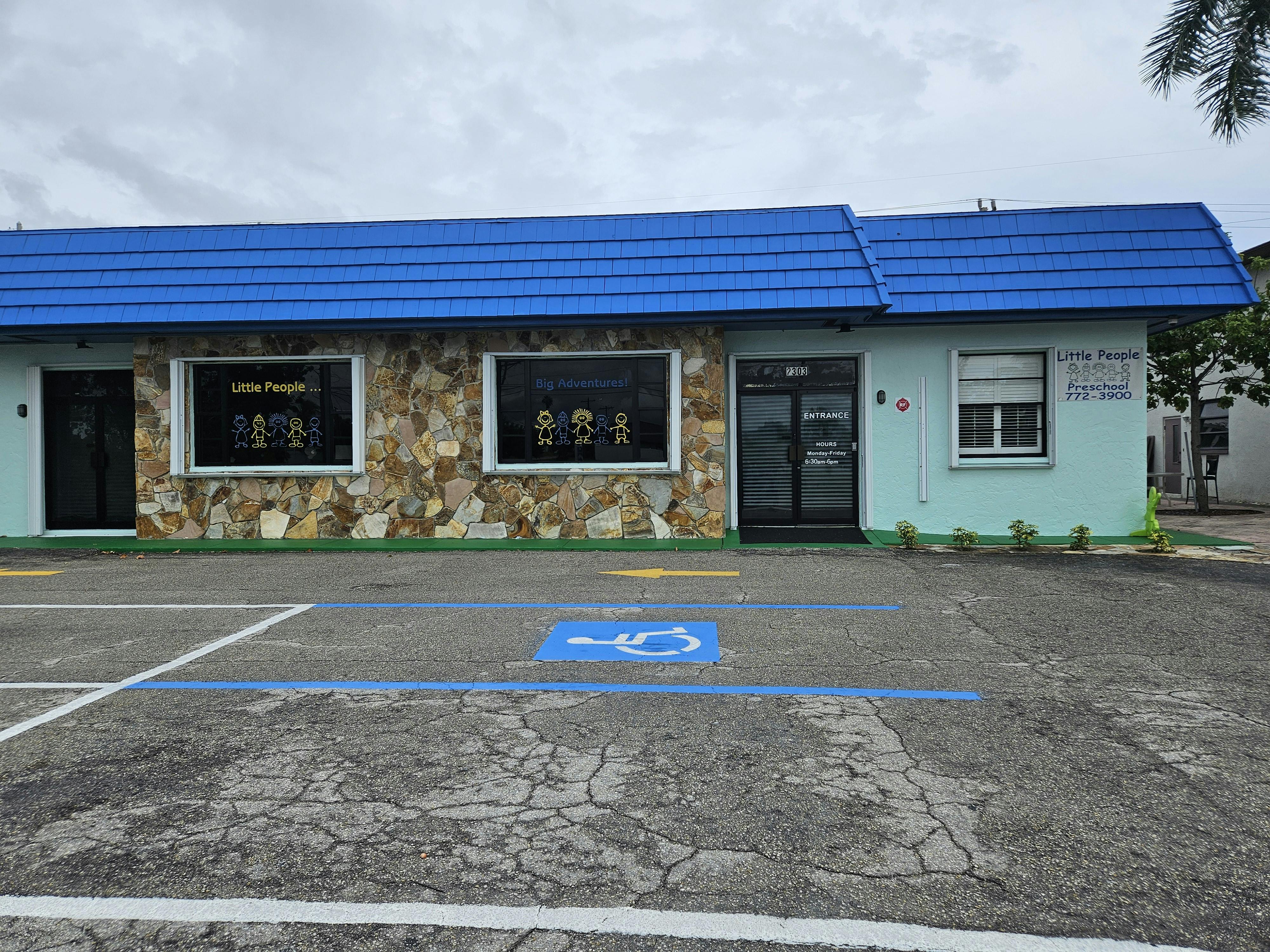 Building with a blue roof and a parking lot with a handicapped parking space
