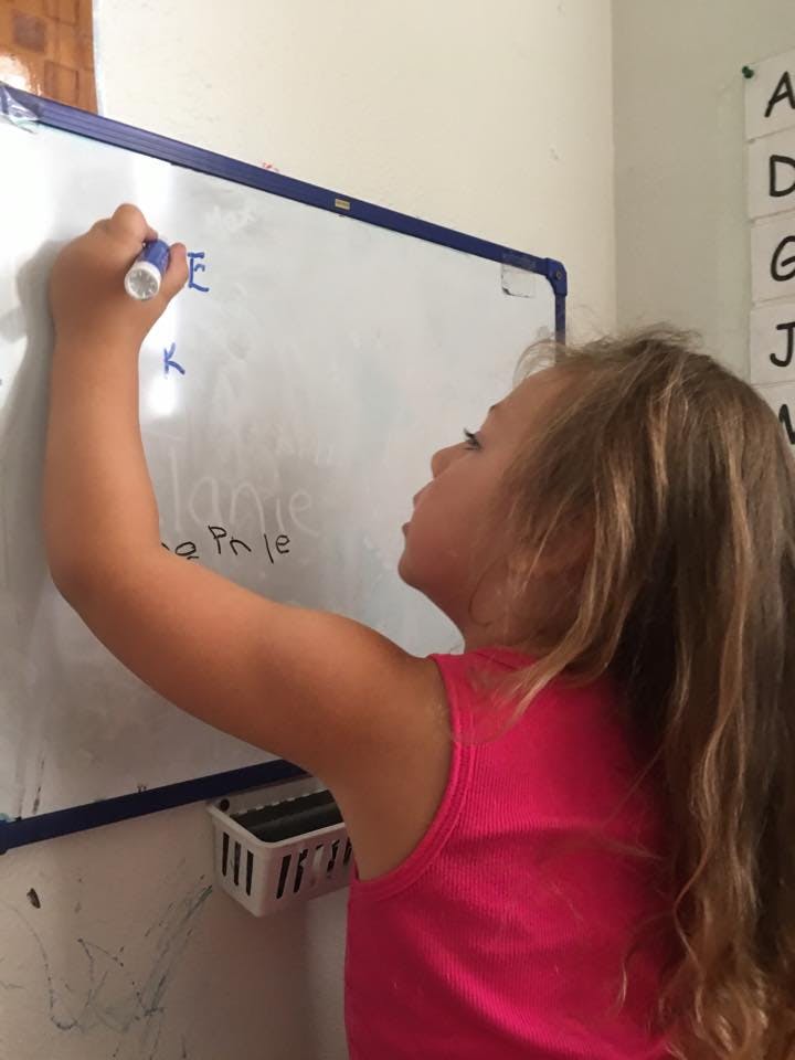 Child writing on a whiteboard with a marker