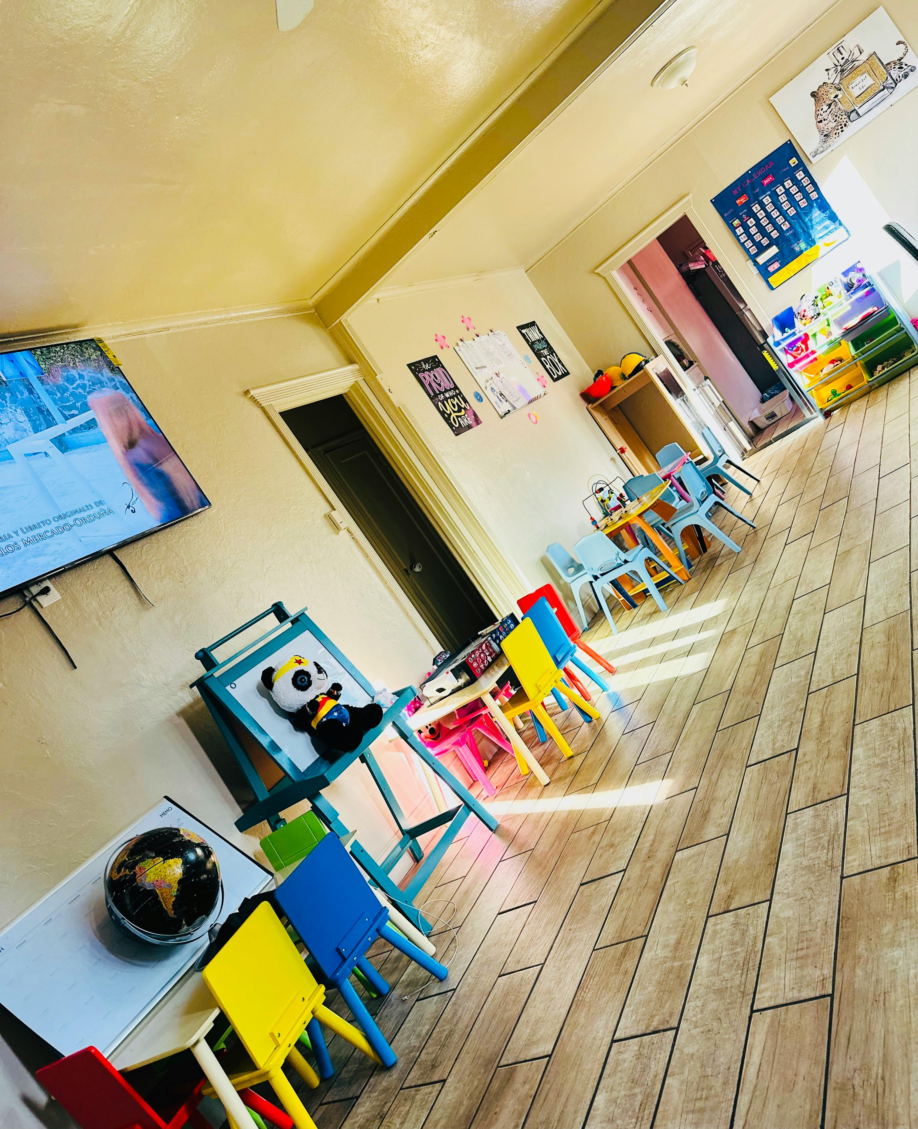 Classroom with small colorful tables and chairs, a TV, and an easel
