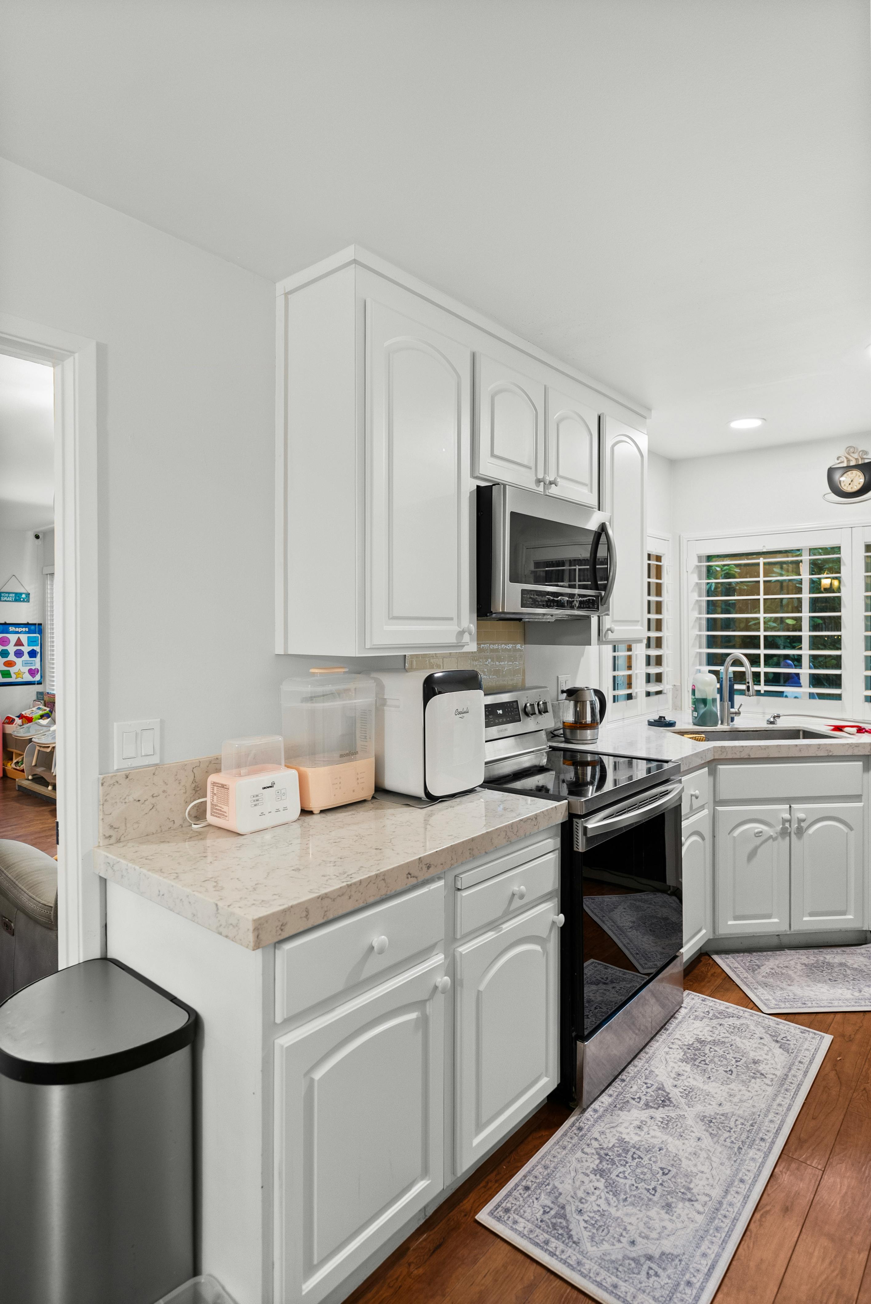 Kitchen with white cabinets, light countertops, and stainless steel appliances