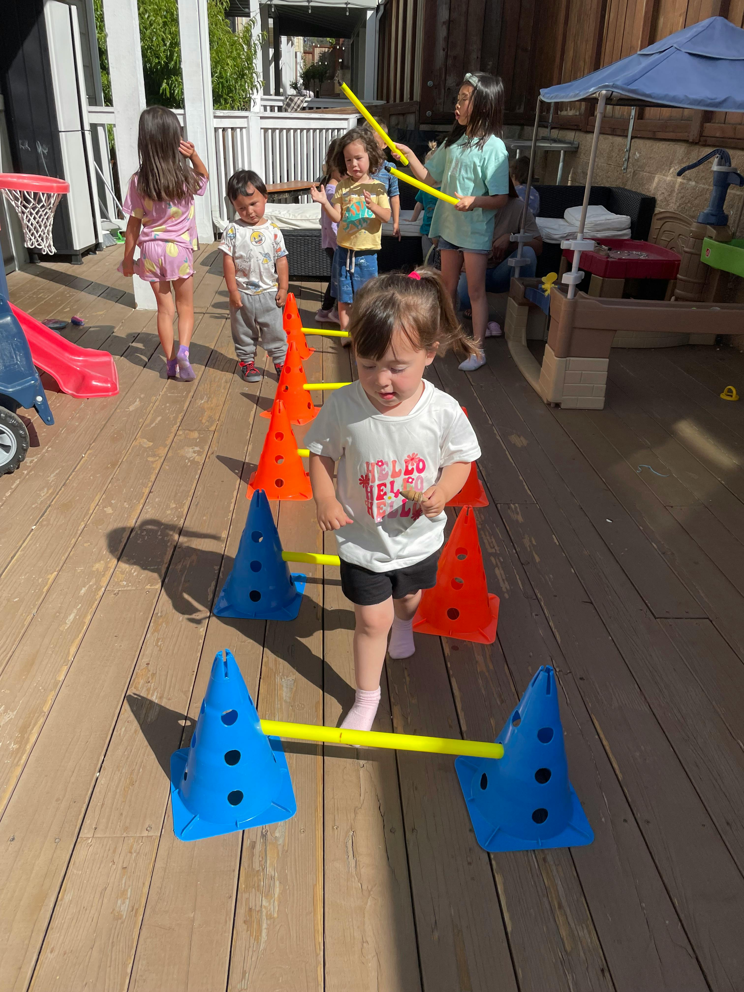 Child walking through an obstacle course of cones and yellow bars