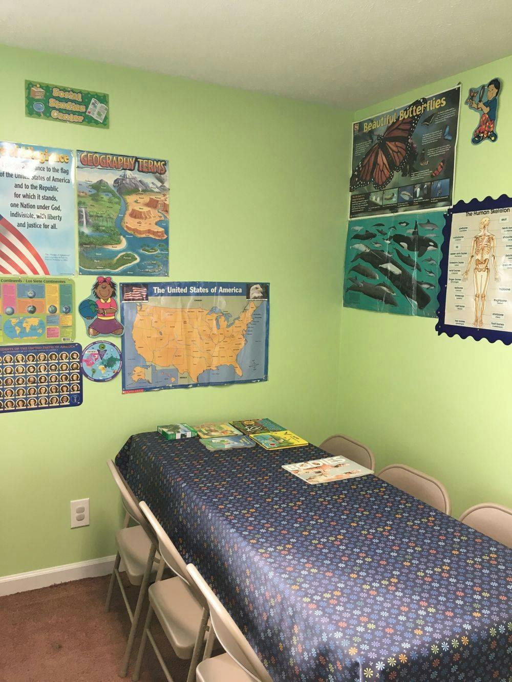 Classroom with posters on green walls and a long table with chairs