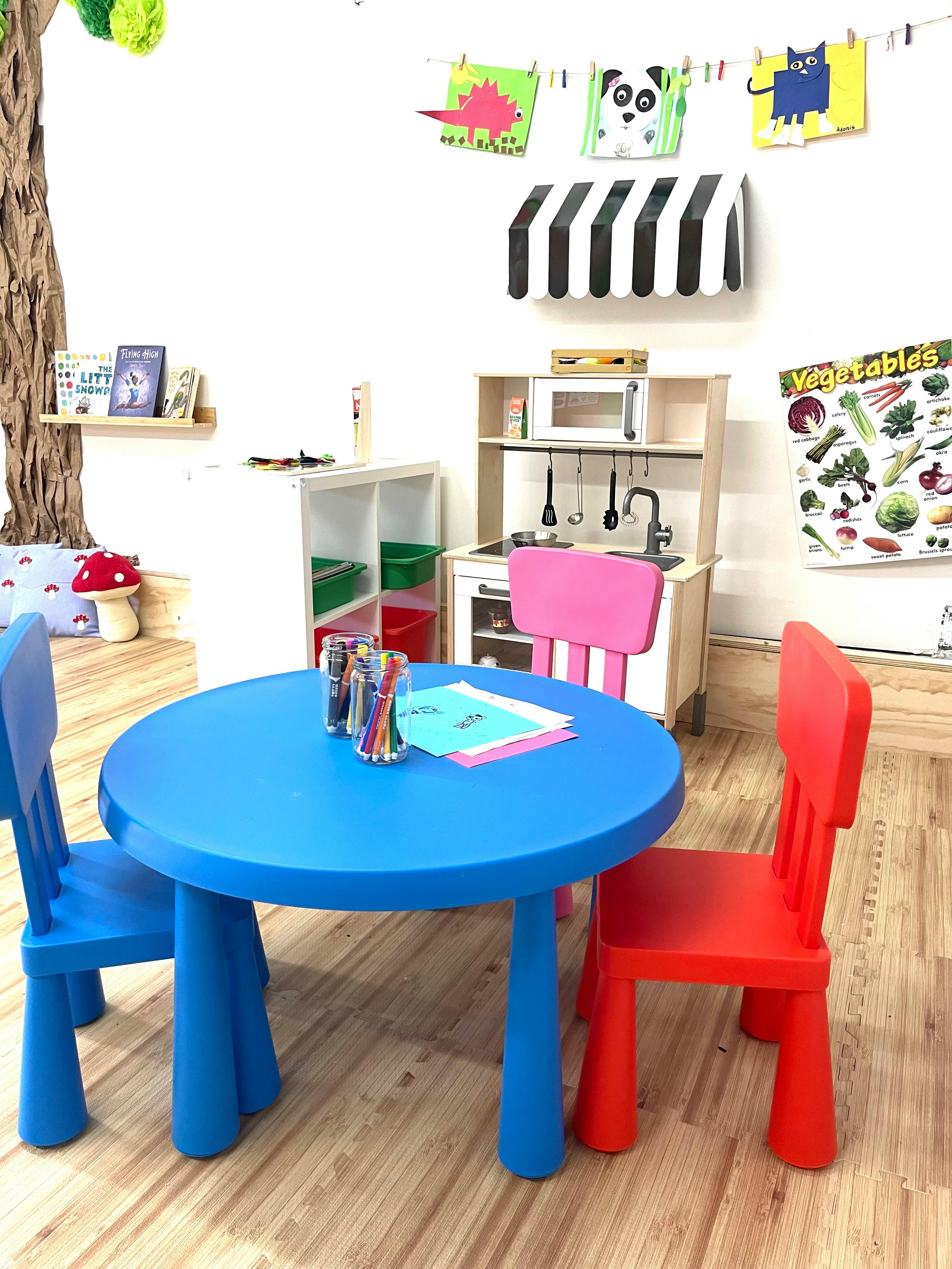 Children's play area with a blue table and chairs, and a toy kitchen