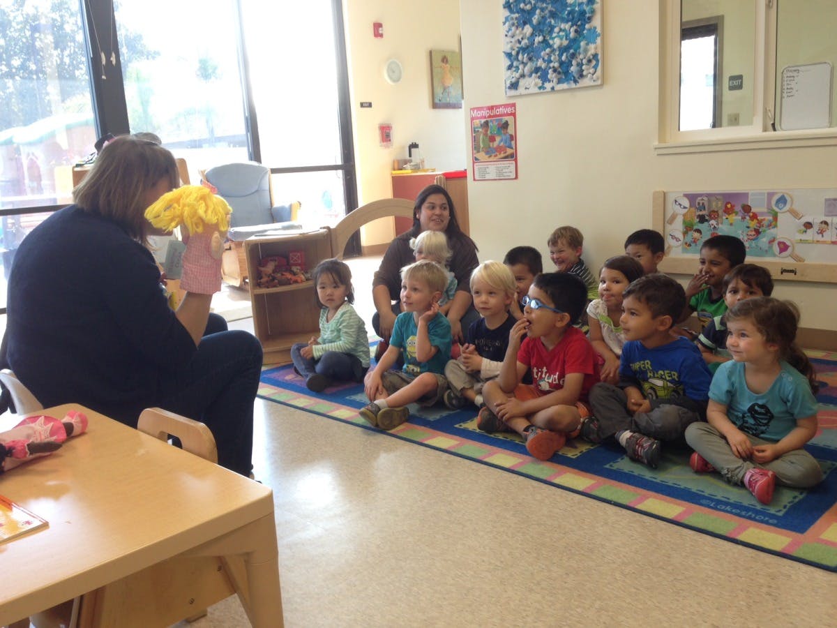 Person using a puppet to entertain children in a classroom