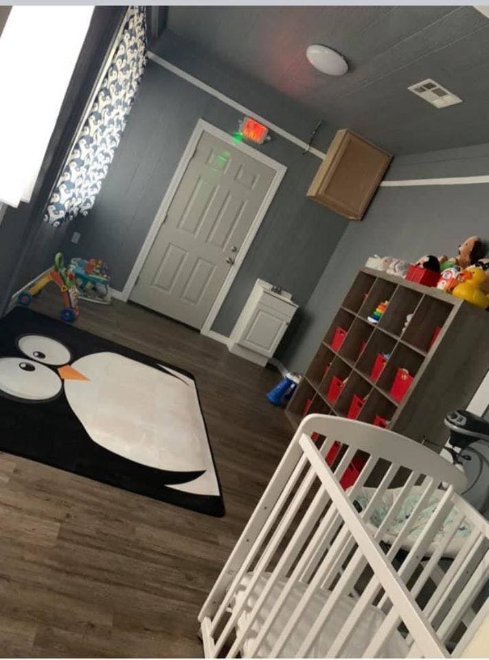 Nursery room with a crib, penguin rug, and storage shelves