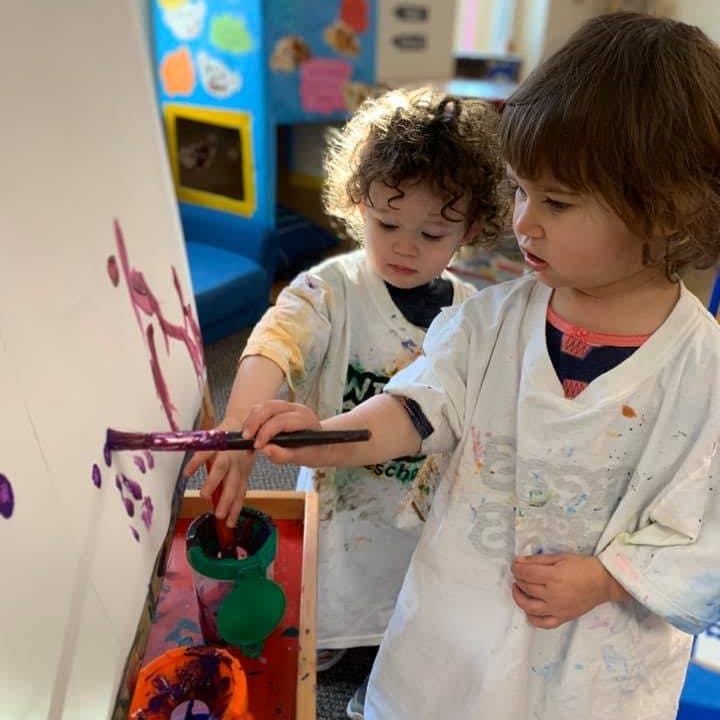 Two children painting on an easel