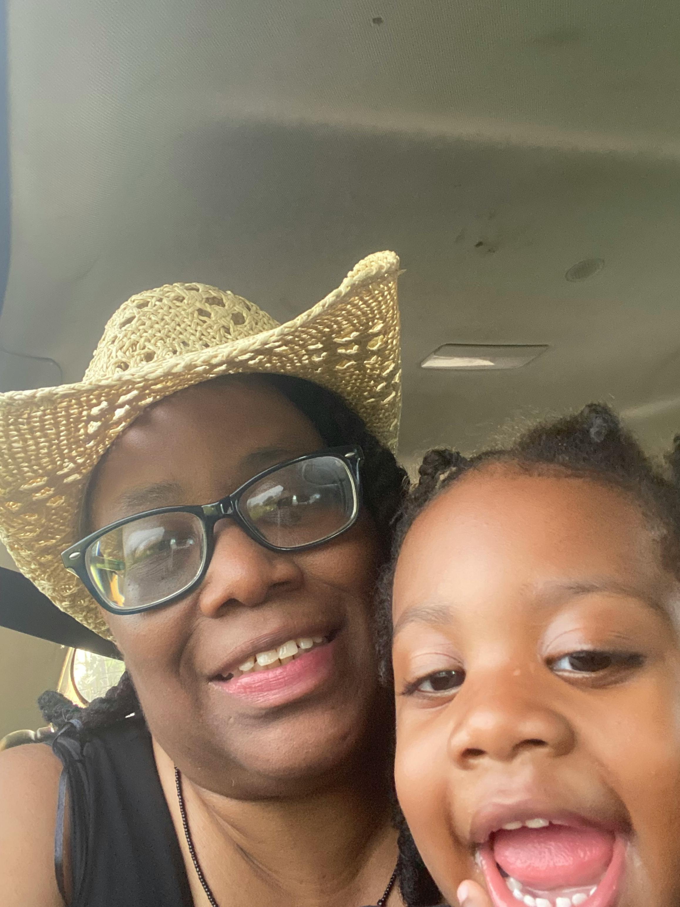 Close-up of a person wearing a straw hat and glasses, with a child above them