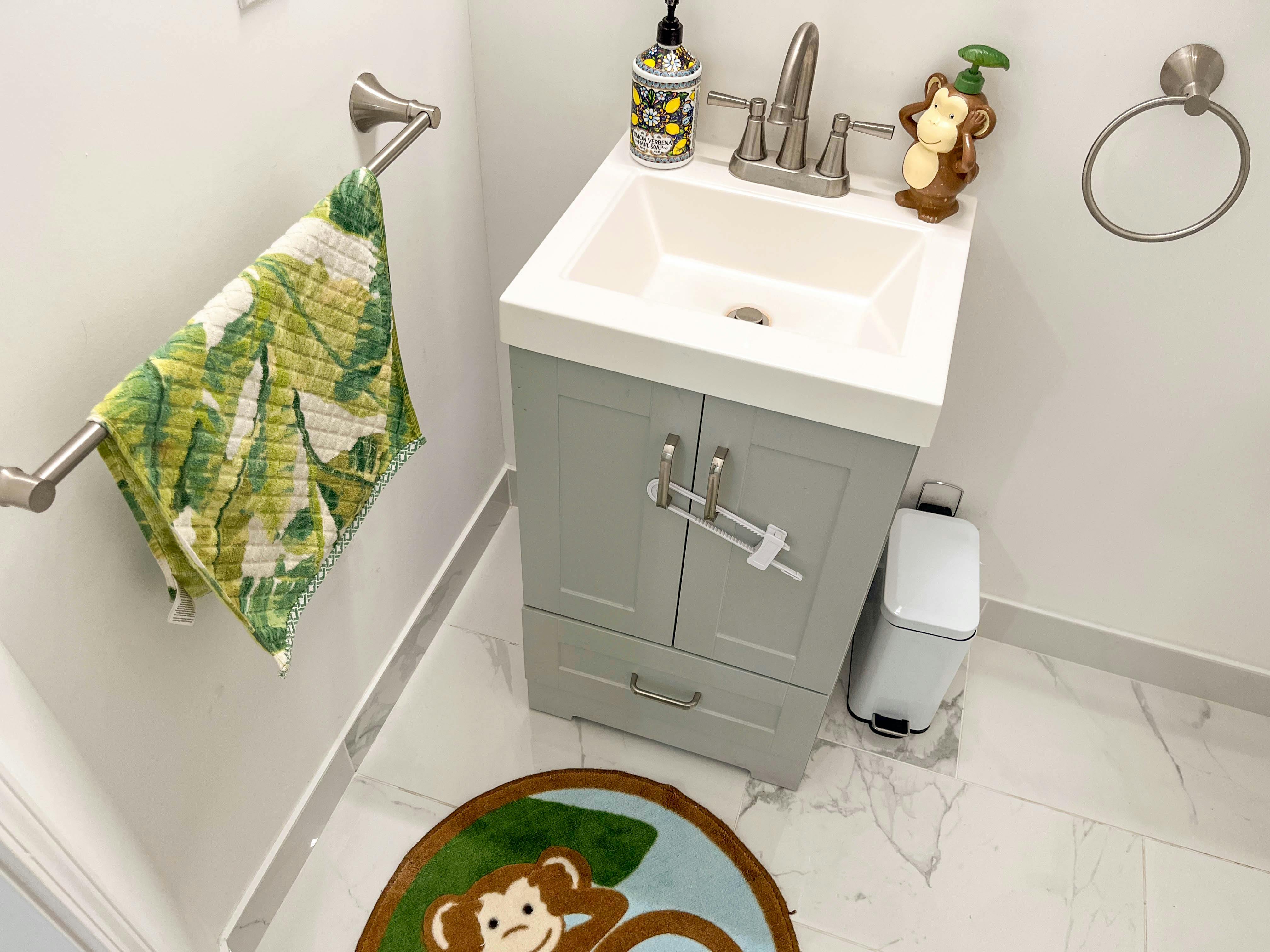 Bathroom vanity with sink, green towel, and monkey bath mat