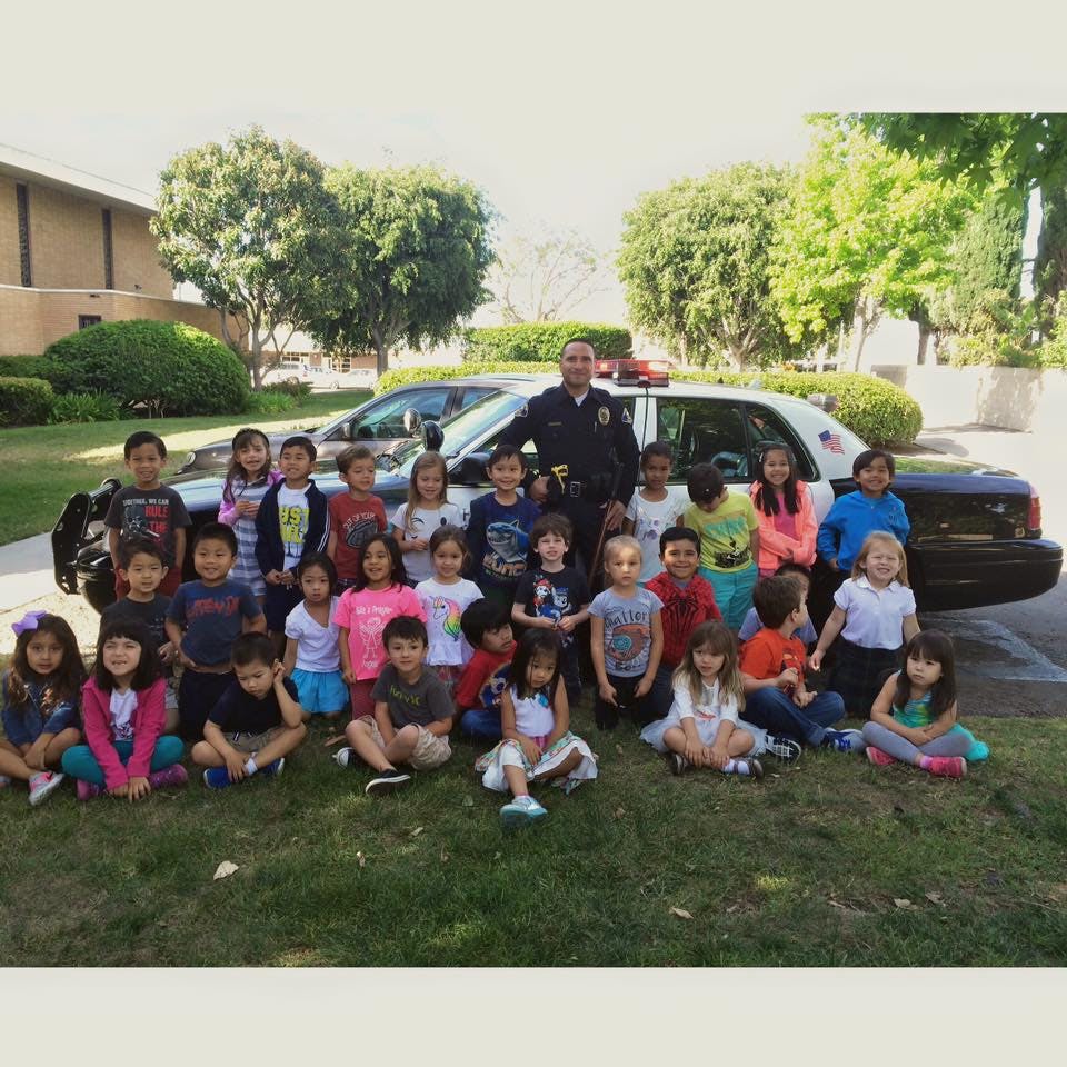 Police officer standing with a group of children in front of a police car