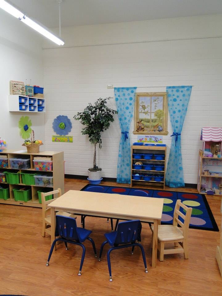 Classroom with small tables and chairs, storage shelves, and a rug