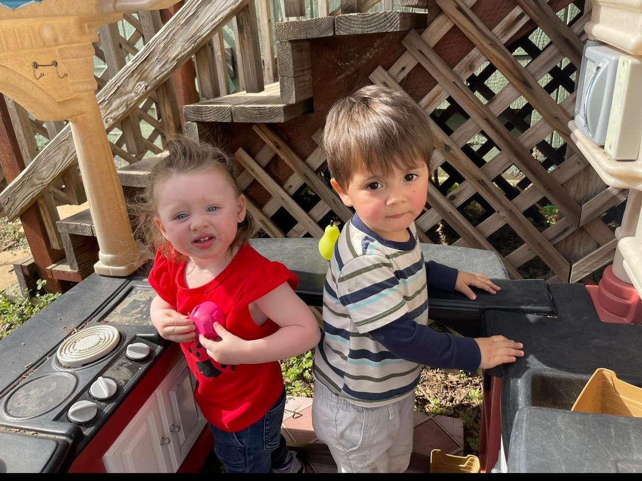 Two children playing at a toy kitchen