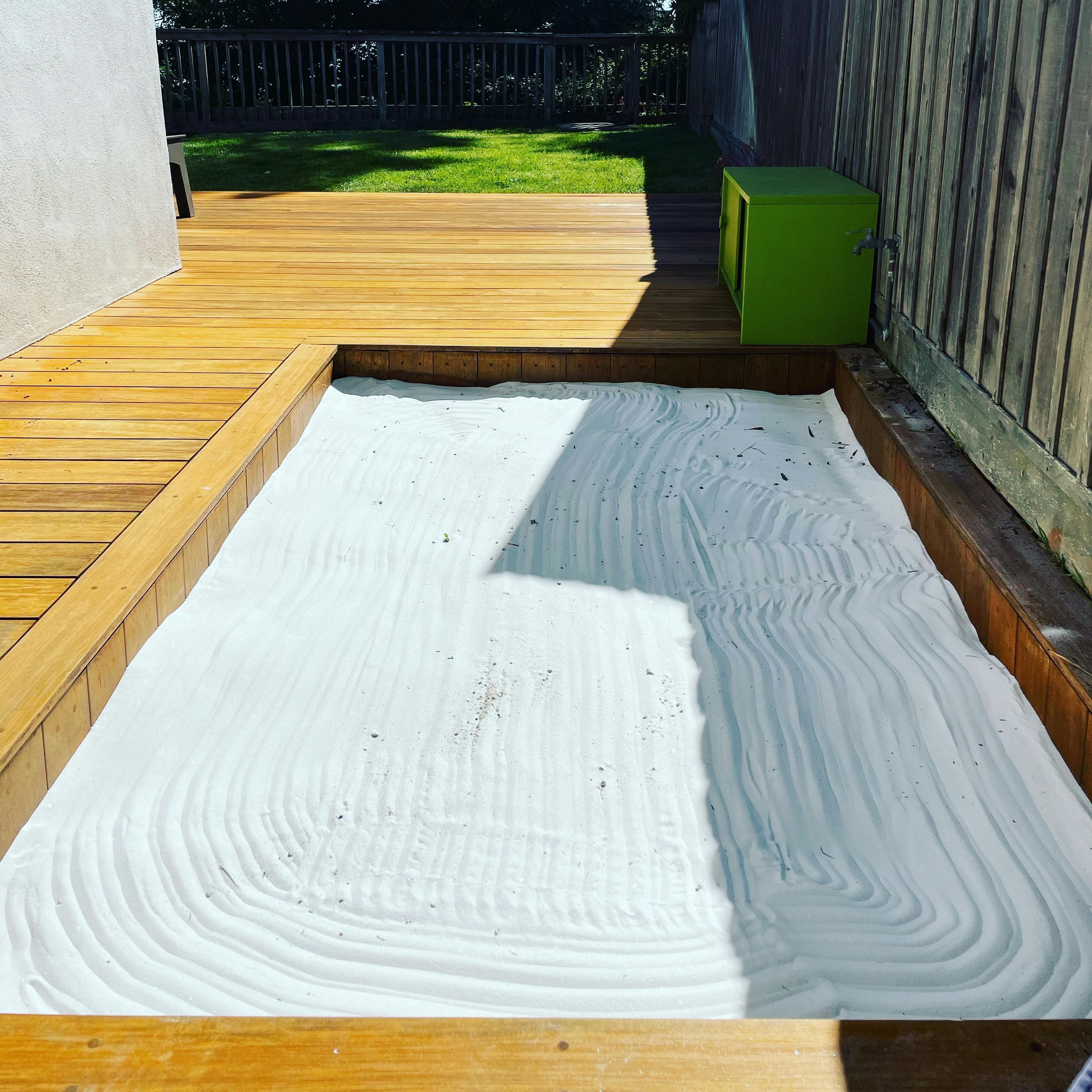 Zen garden with raked sand next to a wooden deck