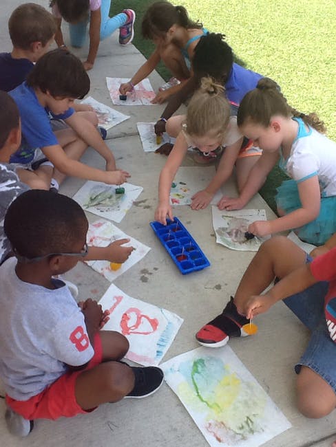 Children painting on paper on the ground
