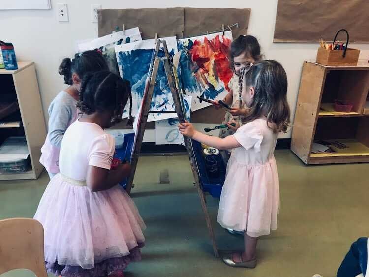 Children painting at easels in a classroom