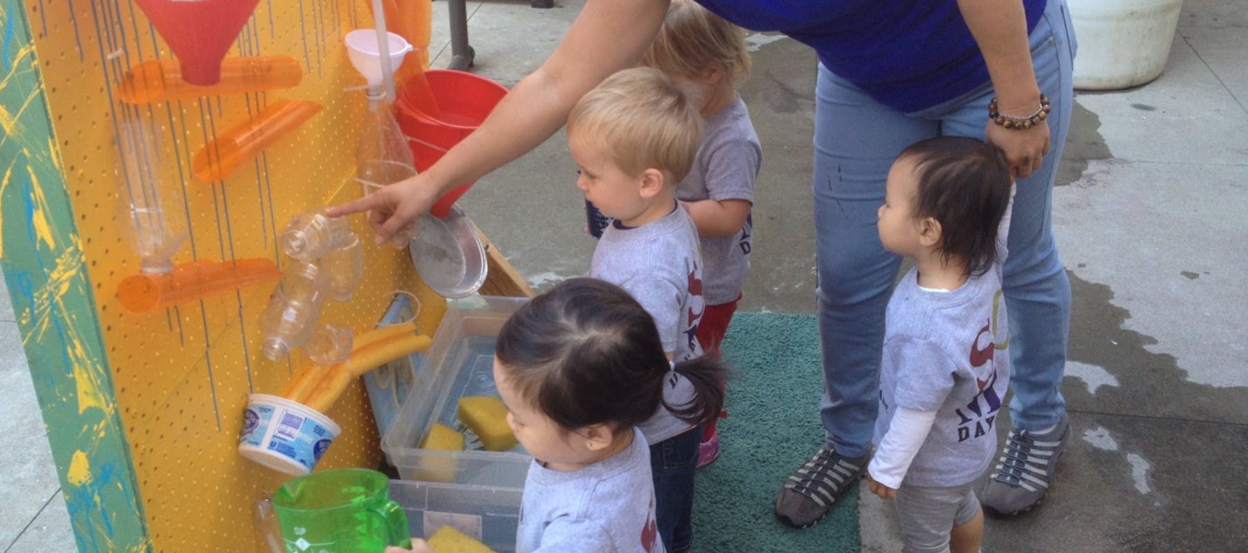 Adult and children playing with a water activity wall