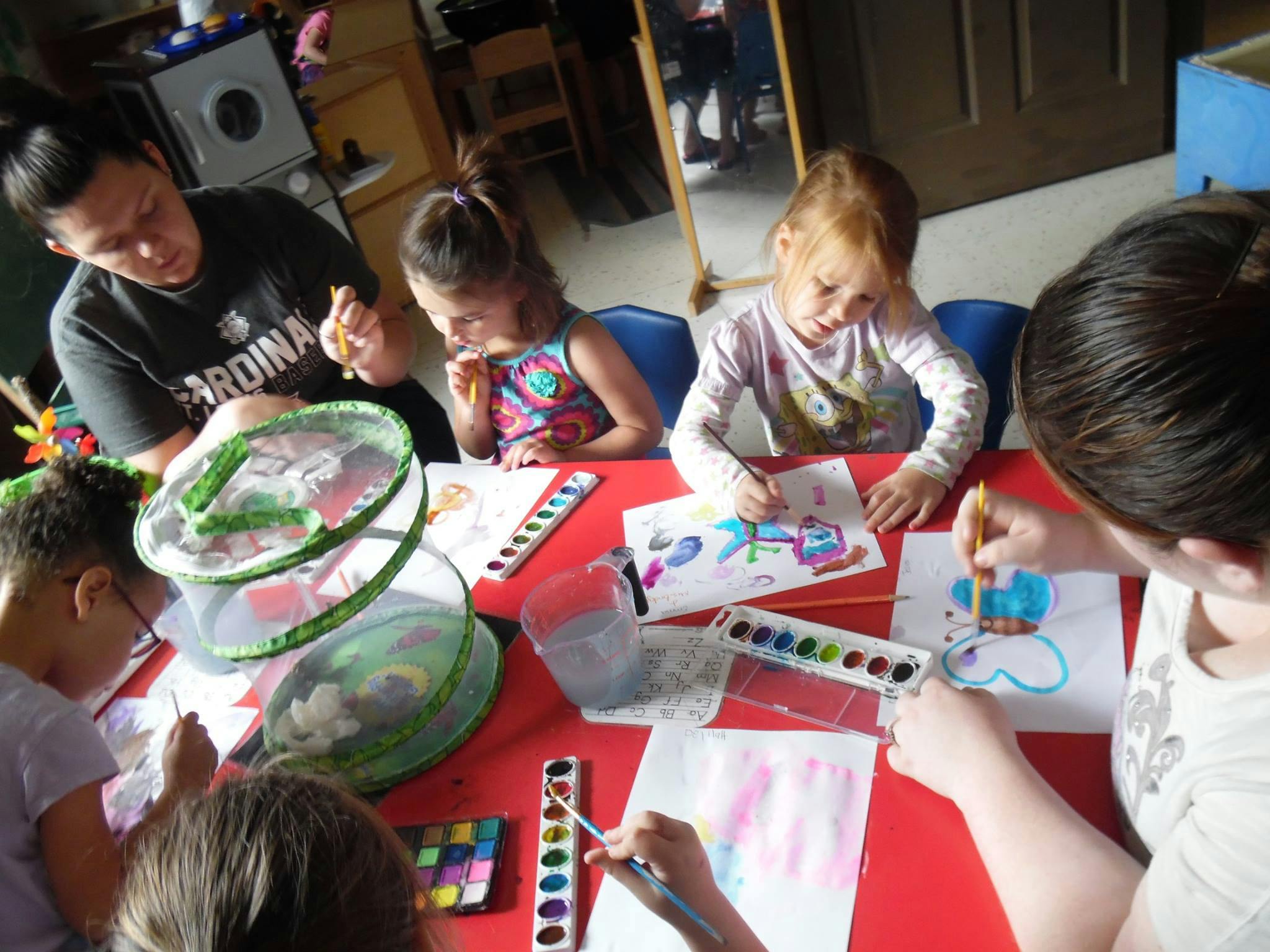 Adults and children painting at a table