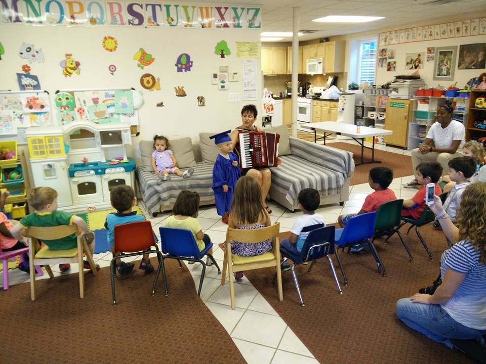 Person playing accordion for children in a classroom